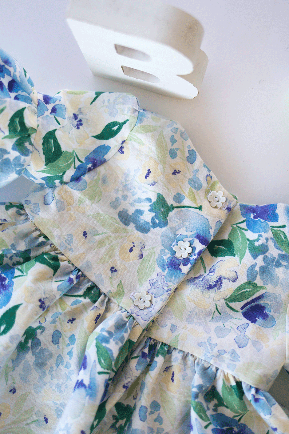 This simple pattern hack will show you how to make a darling on-trend bell sleeve baby dress DIY for the little bundle of joy! Take a break from pink by using this beautiful blue and green floral fabric; it's the perfect addition to any little girls' wardrobe. Read on for the ruffle sleeve tutorial and details on this gorgeous quilting cotton.